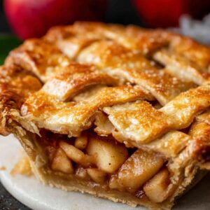 Close-up of a golden-brown baked apple pie slice showing caramelized apple filling and flaky crust.