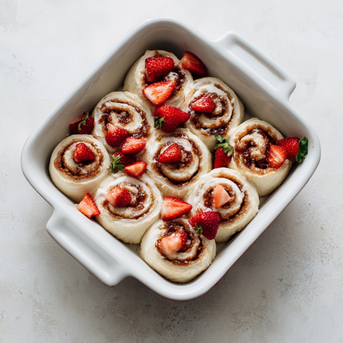 Step-by-step collage showing preparation of strawberry cheesecake cinnamon rolls from dough to baked rolls with icing.