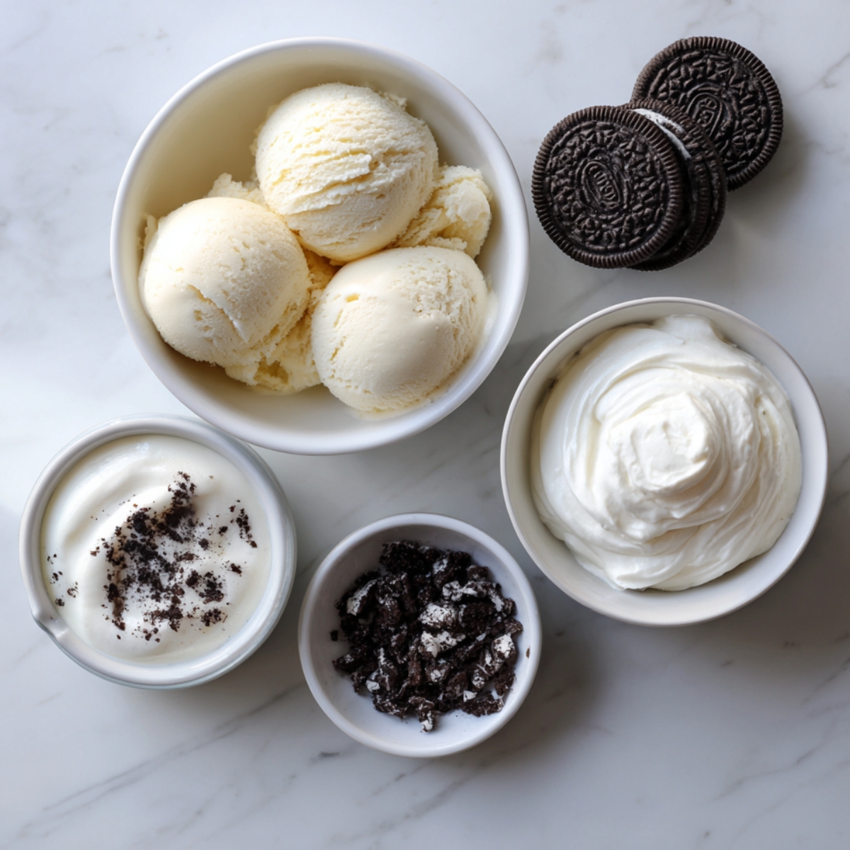 A close-up of milk, cookies, ice cream scoops, and chocolate syrup arranged on a light background.