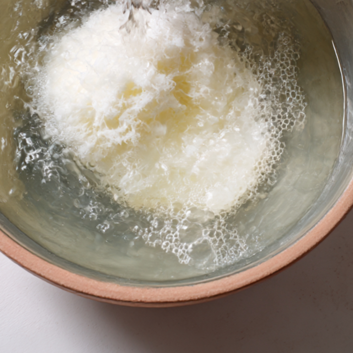 A swirling motion in a pot where dough or milk is being mixed into a frothy, bubbling texture.