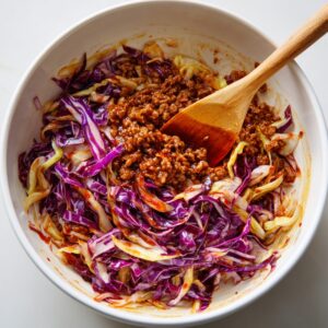 A close-up of a cooked egg roll bowl with ground meat and shredded vegetables, mixed together.