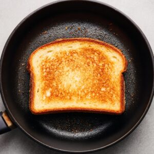 "Golden brown slice of French toast cooking in a non-stick pan."