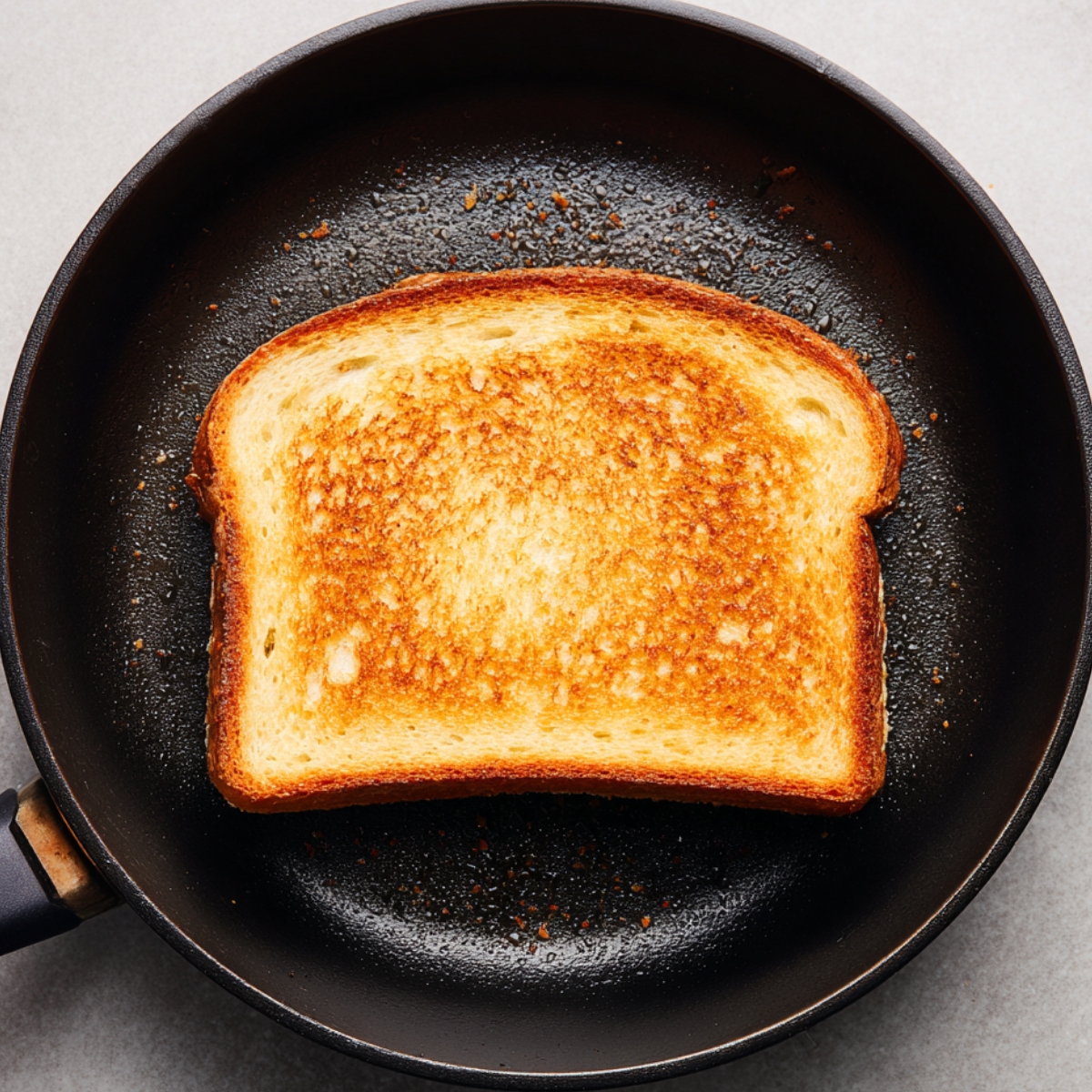 "Golden brown slice of French toast cooking in a non-stick pan."