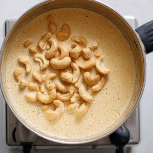 A close-up shot of a pan filled with cashew nuts floating on top of a creamy liquid mixture.