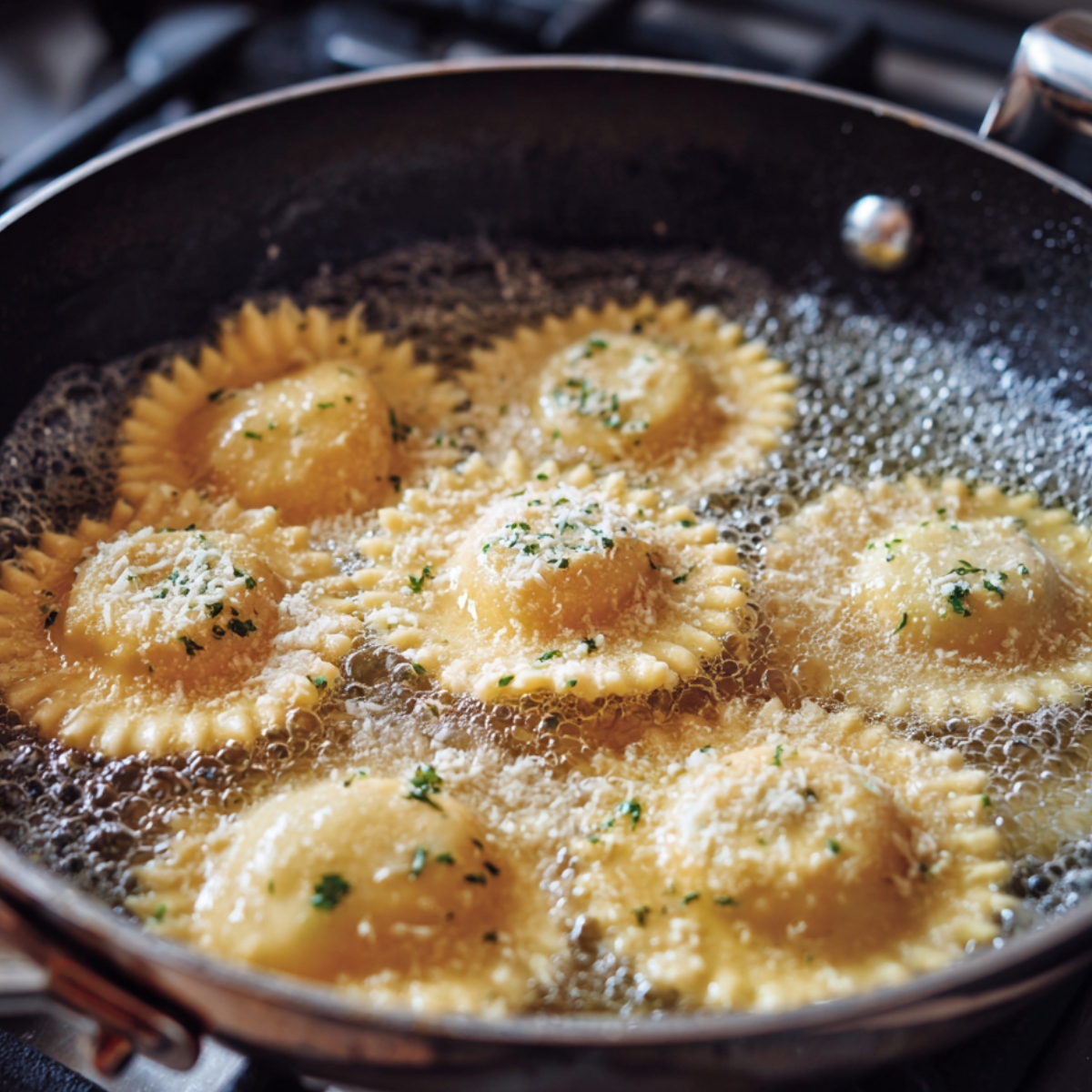 Ravioli frying in a skillet, bubbling in hot oil with grated cheese sprinkled on top.