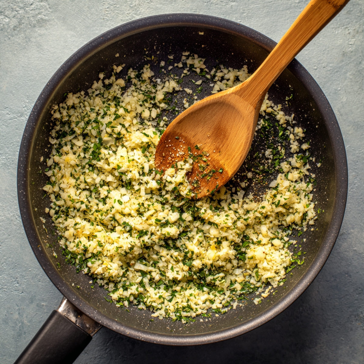 A skillet with sautéed garlic and herbs, finely chopped in a mixture.