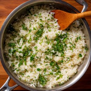 A pot of fluffy cilantro-lime rice with chopped fresh herbs stirred in, ready to serve.