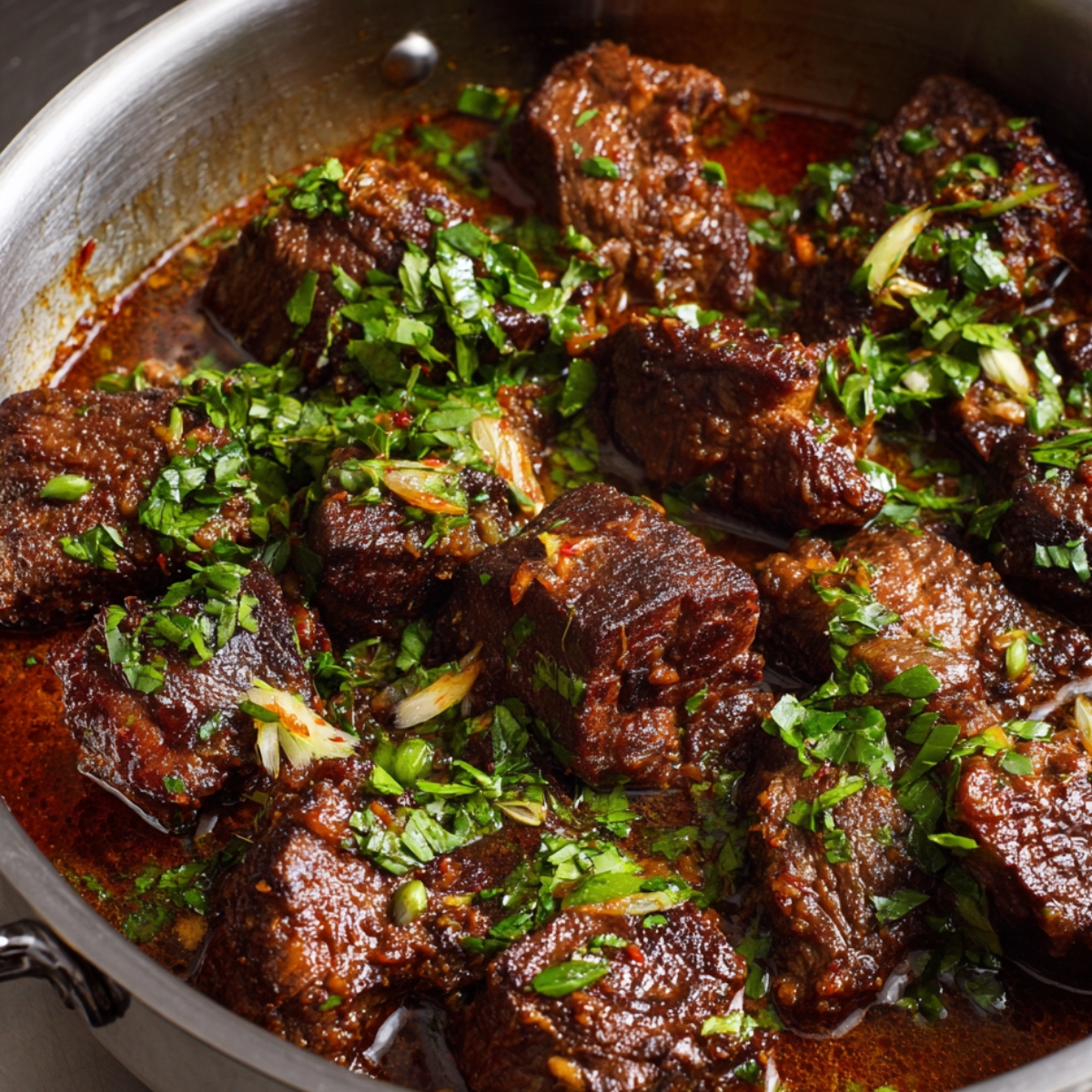 Tender chunks of beef simmering in a flavorful sauce, topped with freshly chopped herbs.
