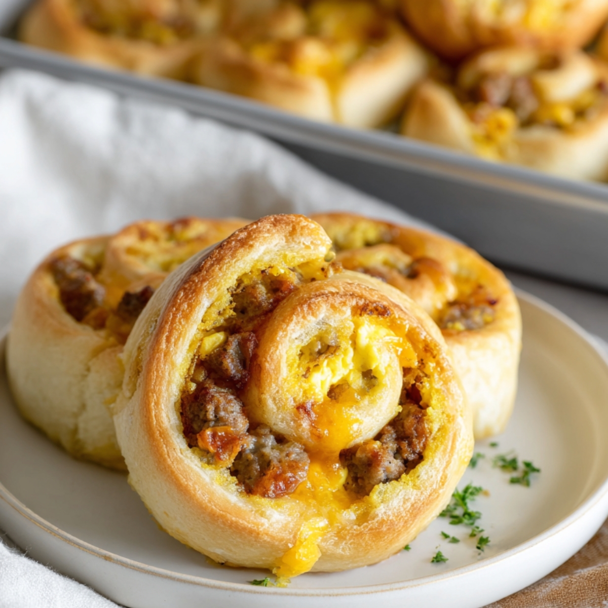 Breakfast Rolls A savory breakfast roll with sausage, cheese, and scrambled eggs, served on a plate.