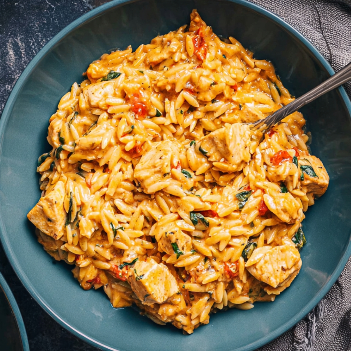 Creamy Cajun Chicken Orzo 
 served in a teal bowl, made with tender chicken pieces, orzo pasta, spinach, and a rich orange Cajun cream sauce.