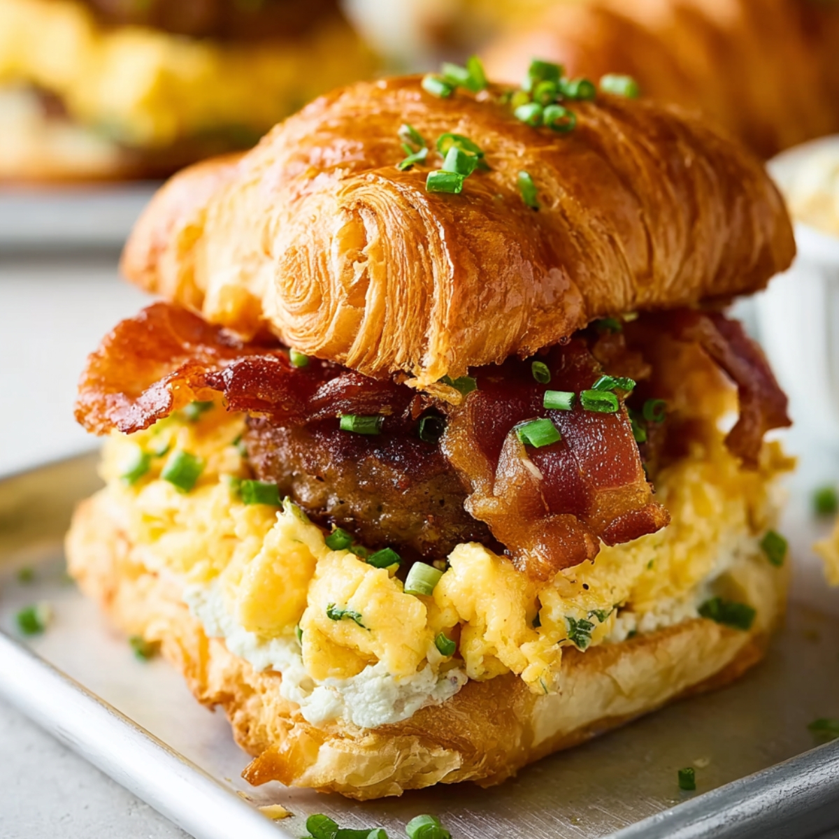 Cheese Breakfast Croissant Sandwiches A delicious croissant breakfast sandwich filled with scrambled eggs, sausage patty, crispy bacon, and topped with fresh chives