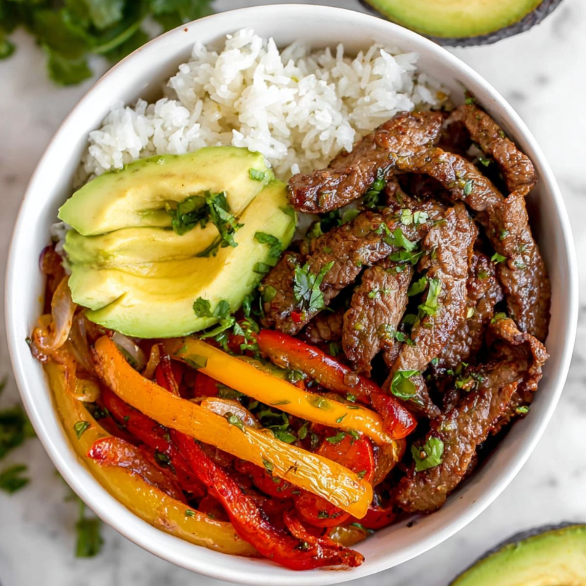 Beef Fajita Bowls
 A vibrant and appetizing keto beef fajita bowl, featuring tender marinated beef strips served with a side of colorful sautéed bell peppers and onions. The dish is complemented by creamy avocado slices and a generous serving of fluffy white rice, all garnished with fresh cilantro. The combination of fresh ingredients and savory beef creates an enticing, wholesome meal.