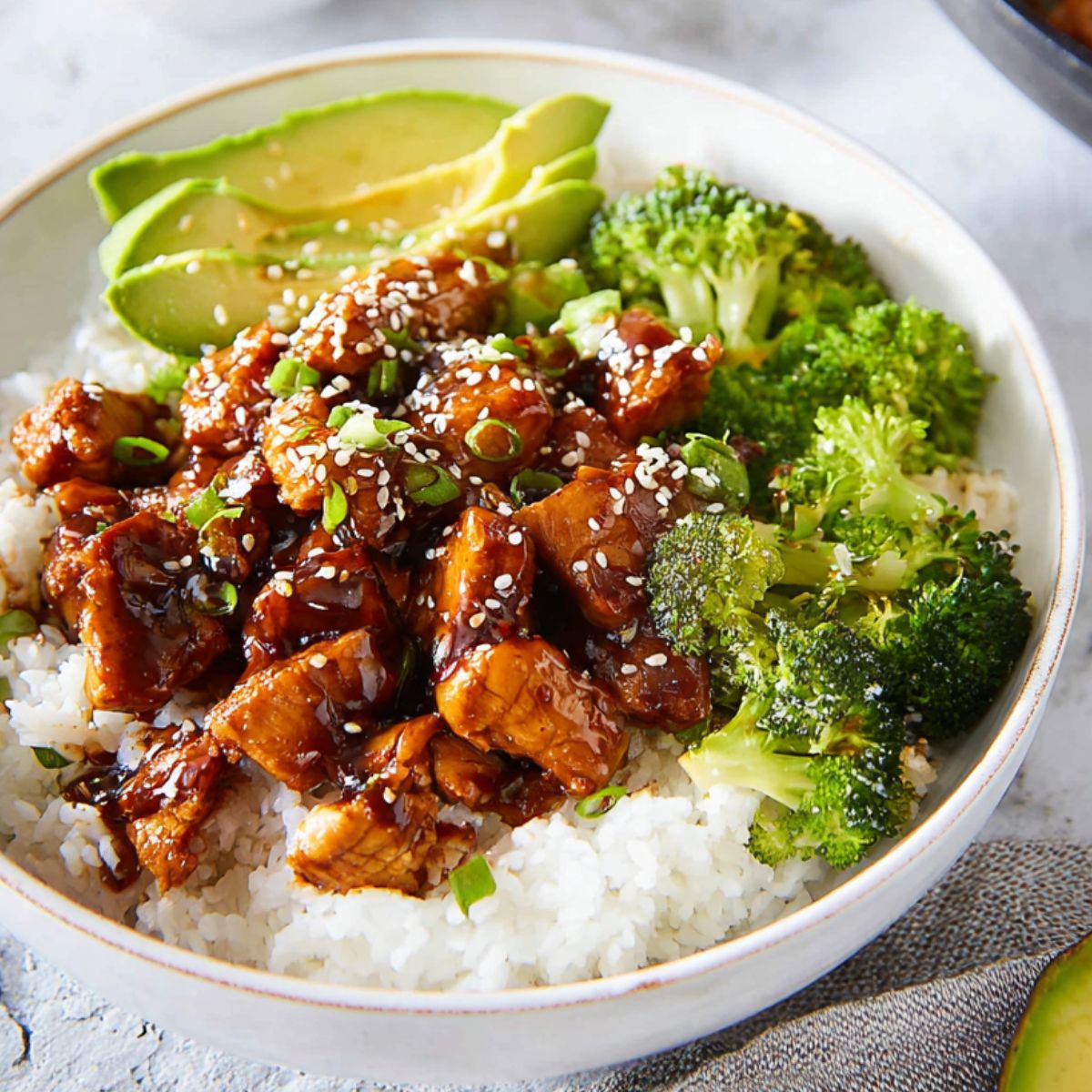 Teriyaki Chicken and Rice Bowls
Present a final shot of a wholesome teriyaki chicken rice bowl, featuring tender chicken pieces covered in a rich teriyaki sauce, served on a bed of fluffy white rice. The bowl is adorned with fresh broccoli, creamy avocado slices, and a sprinkle of sesame seeds and sliced green onions. The scene exudes warmth and balance, offering a comforting, healthy meal.
