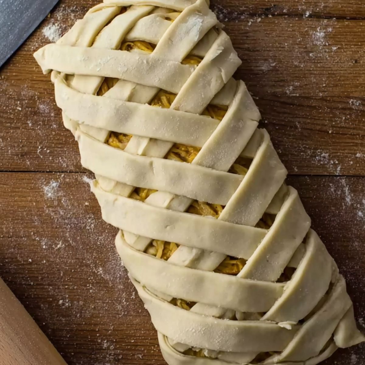 Here, the dough is skillfully braided over the savory filling, which could be a mix of scrambled eggs, cheese, and sausage. The lattice design on top adds an elegant touch, ensuring a crispy, golden exterior once baked.