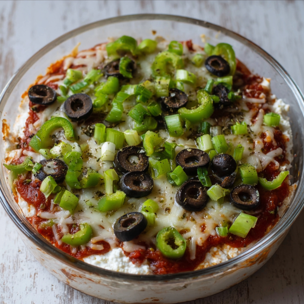 A cozy cottage cheese pizza bowl, topped with mozzarella, olives, and fresh veggies for a satisfying snack or meal!"