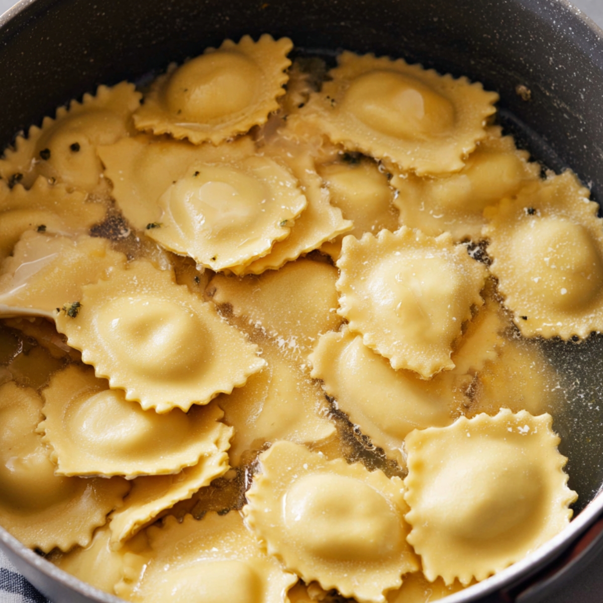 Cheese ravioli simmering in boiling water in a pot, cooking until tender for creamy Tuscan ravioli.