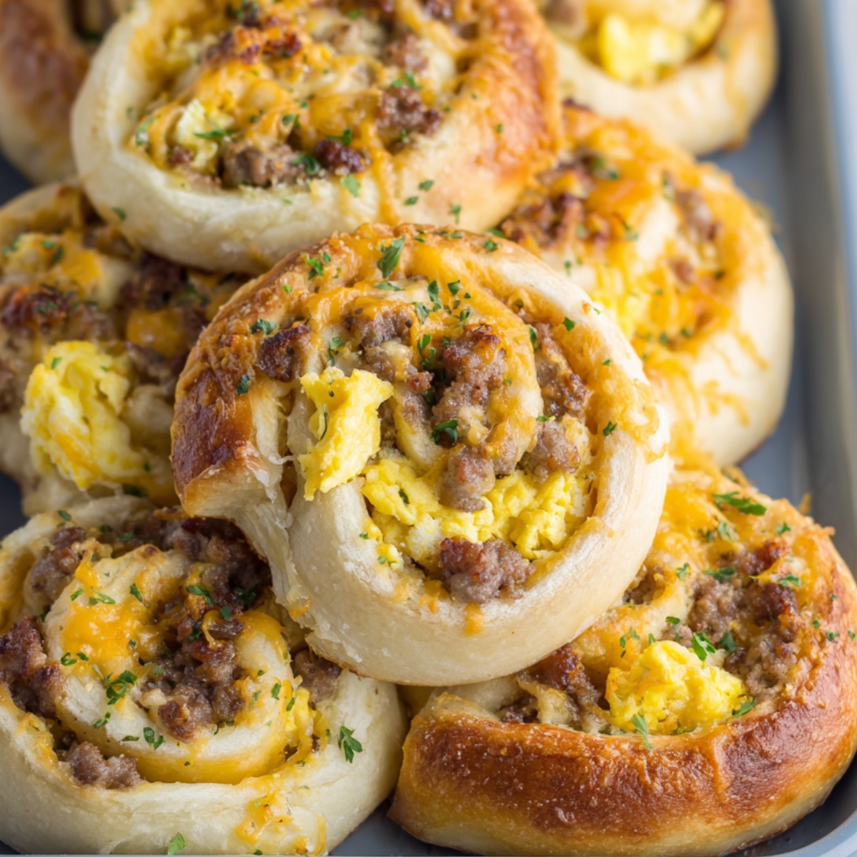 Freshly baked breakfast rolls filled with scrambled eggs, sausage, and melted cheese, creating a savory, cheesy breakfast treat perfect for brunch or quick morning meals