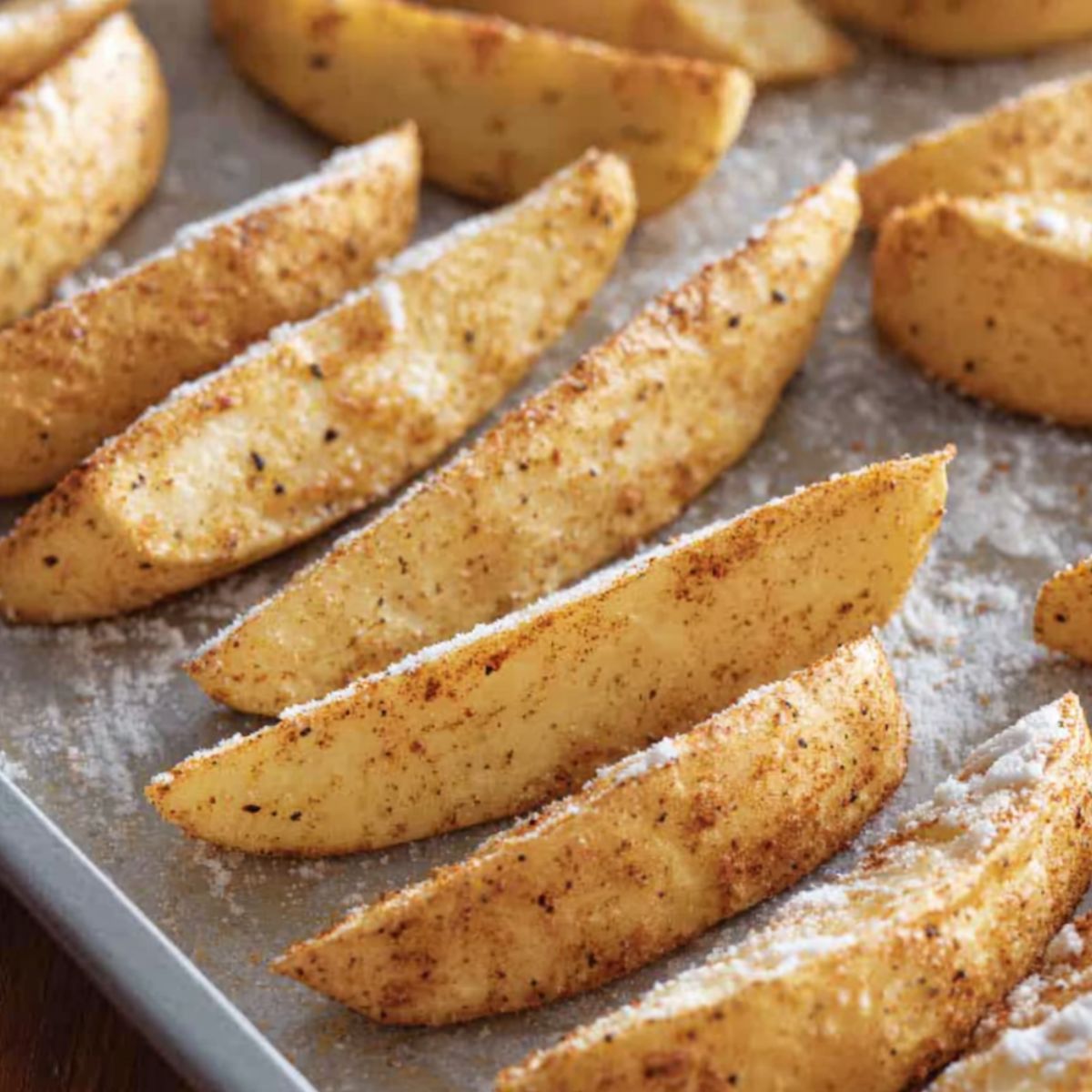 Golden, crispy potato wedges seasoned with spices, perfectly baked to achieve a crunchy, flavorful exterior while maintaining a soft and tender interior.