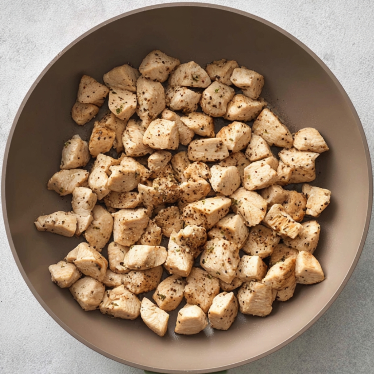 A close-up of diced chicken pieces, seasoned and cooked, ready to be added to the casserole for the next steps.