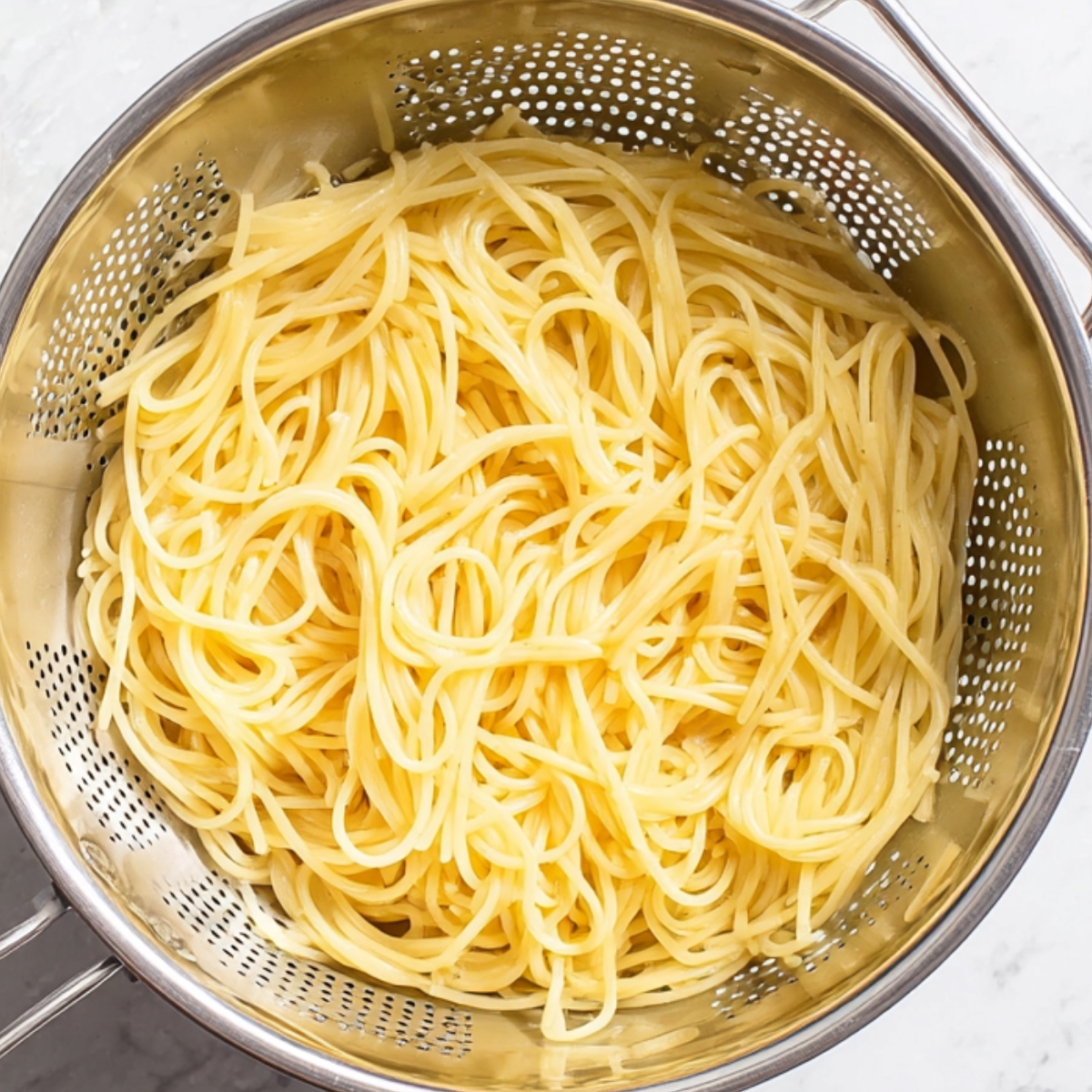 Freshly cooked spaghetti noodles draining in a colander, ready to be added to your favorite pasta dish.