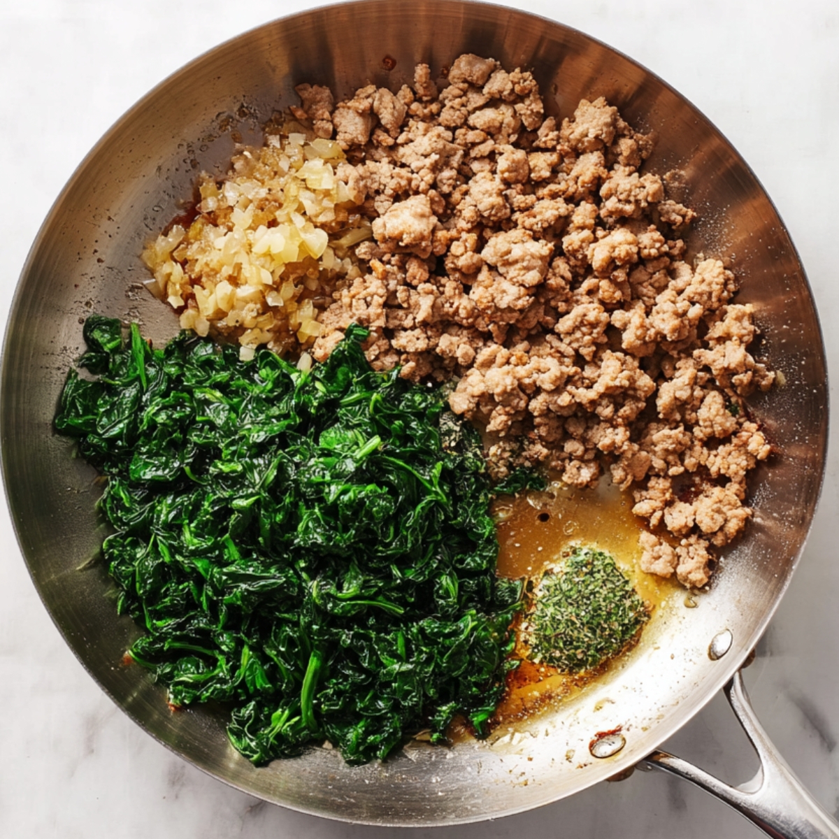 A stainless steel skillet filled with browned ground pork, minced garlic, brown sugar, soy-based sauce, and chopped cooked spinach, partially mixed on a light marble surface.