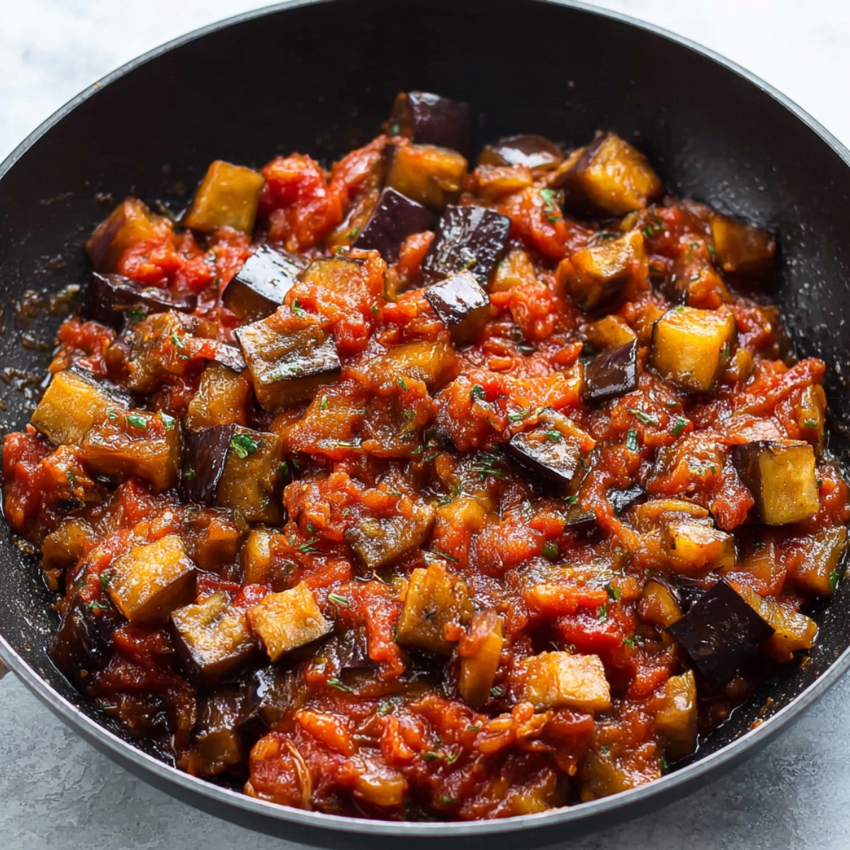Close up of sautéed eggplant immersed in a rich tomato sauce, creating a savory and comforting dish.