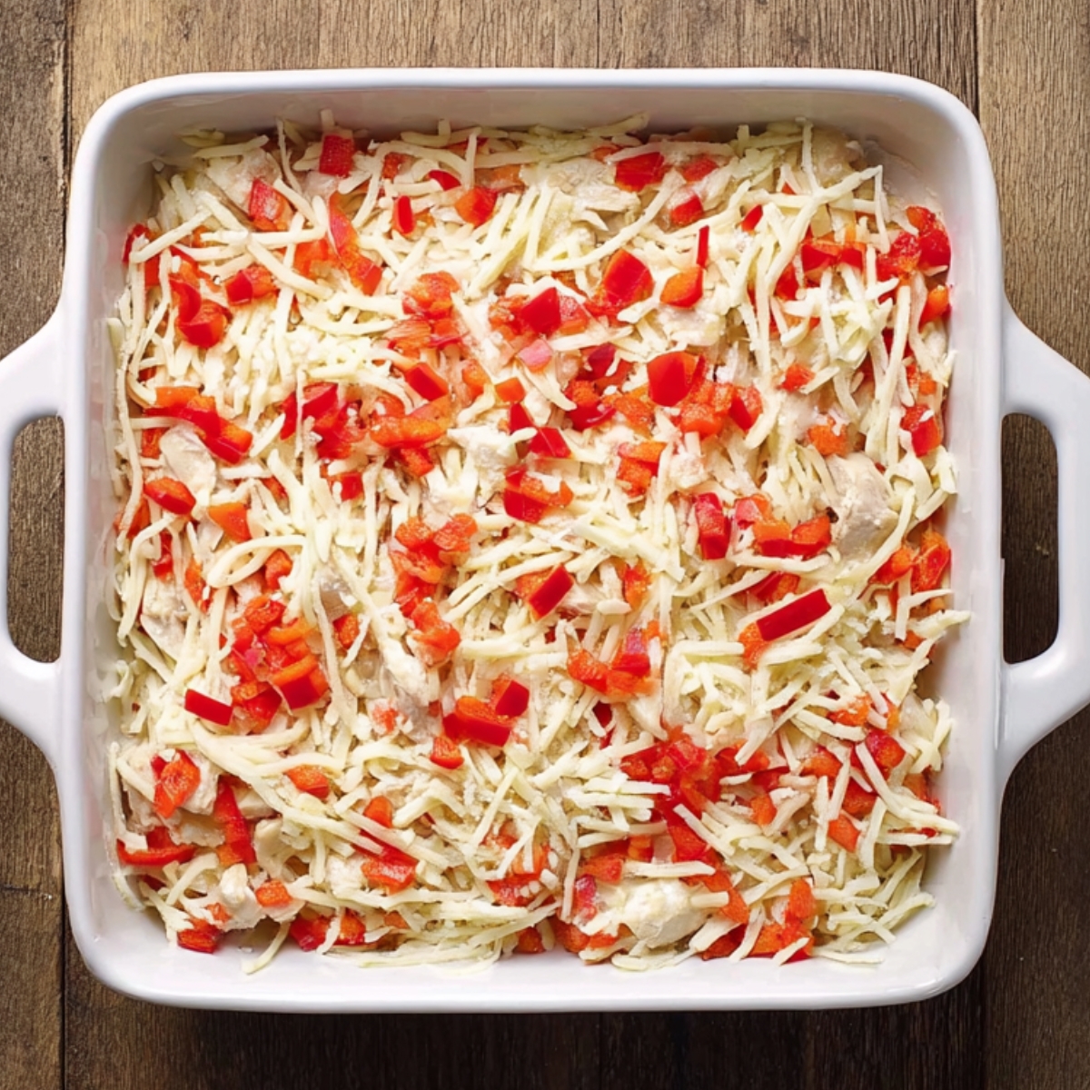 Assembling Salsa Verde Chicken Casserole: The second image depicts the layered preparation of the Salsa Verde Chicken Casserole, where shredded chicken, cheese, and diced vegetables are arranged in a baking dish, ready to be baked into a flavorful casserole.