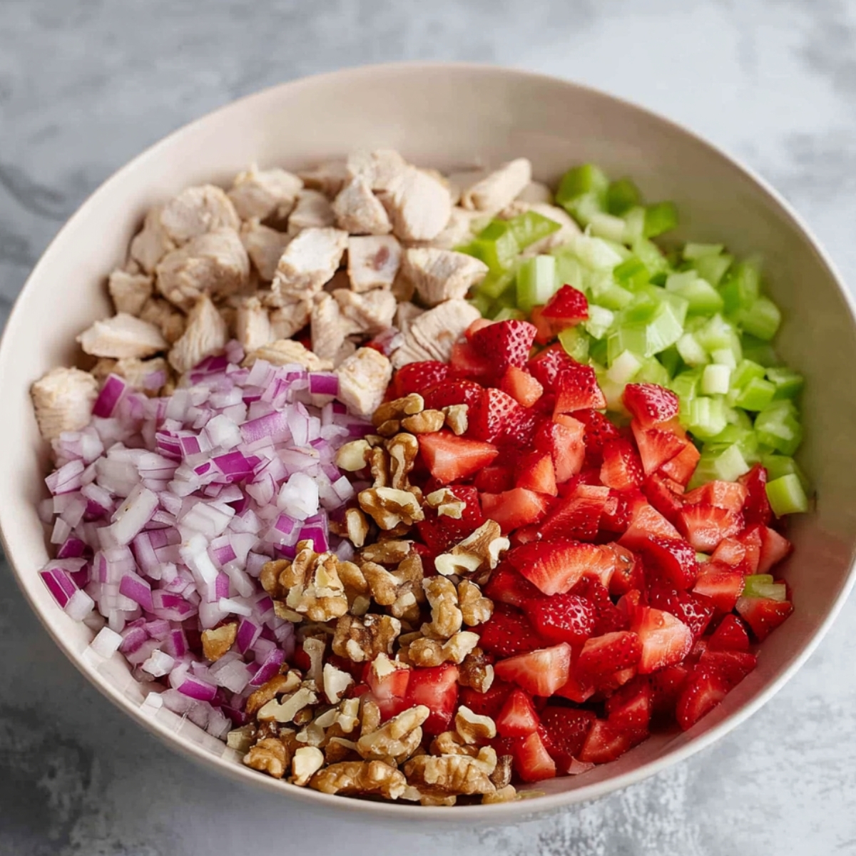 Salad Ingredients Ready to Mix: A close-up of chopped ingredients for a delicious strawberry chicken salad, including tender chicken, ripe strawberries, crunchy celery, red onions, and walnuts—perfectly arranged before mixing.