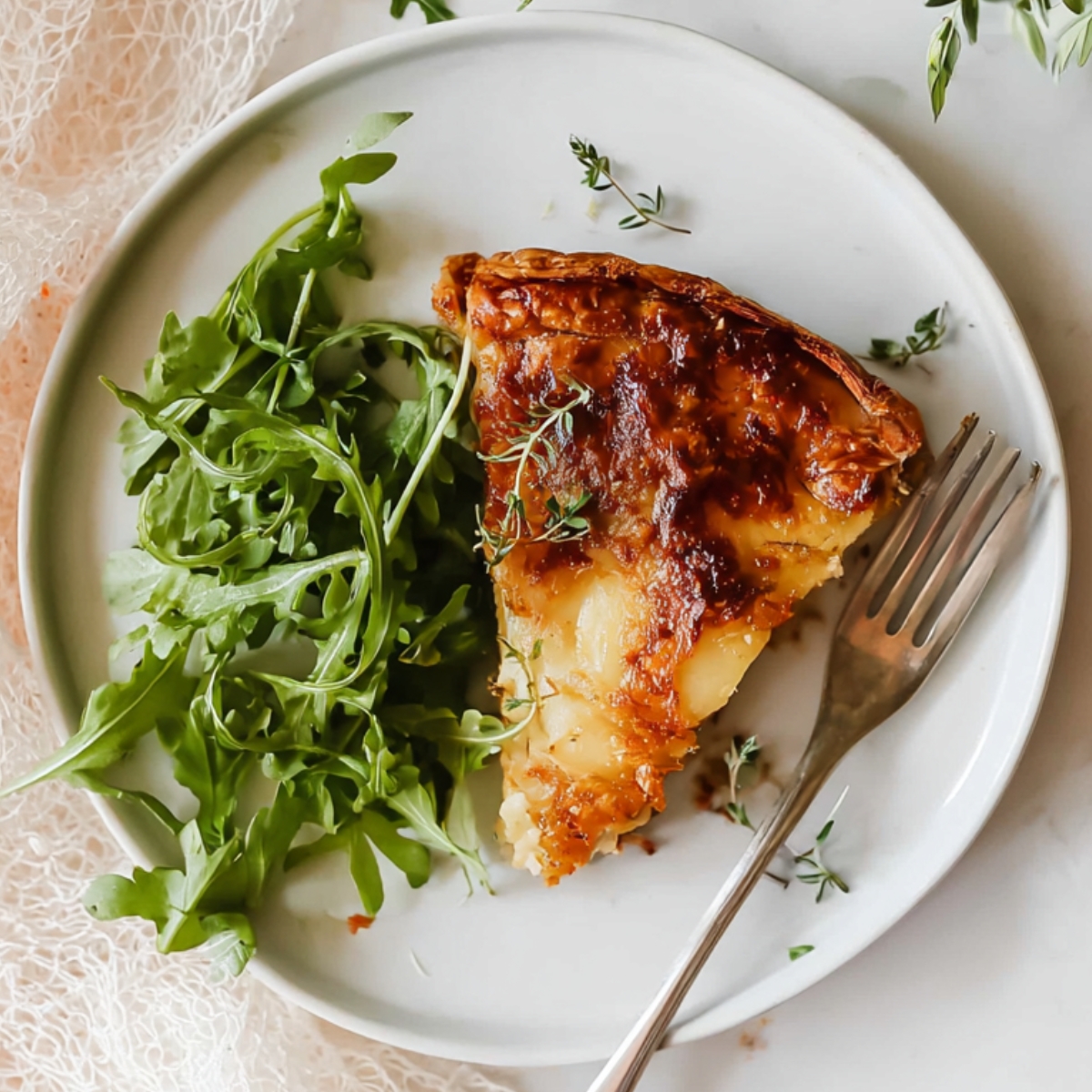 Potato Galette Close up of a slice of cheesy potato galette on a white plate, garnished with fresh arugula, fork resting on the side, natural light highlighting the golden-brown crust, overhead view, styled food photography, minimalistic background with soft textures, cozy and inviting atmosphere.