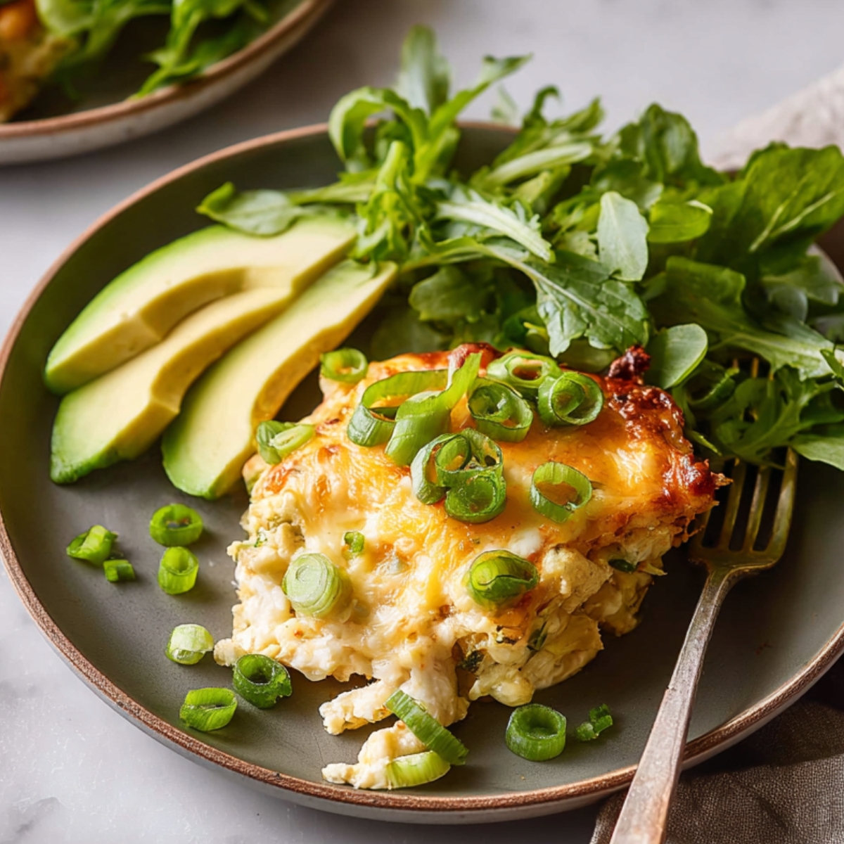 Tater Tot Breakfast Casserole Close up of a creamy baked casserole topped with melted cheese and fresh green onions, served on a modern plate with sliced avocado and a side of leafy greens, soft natural lighting, high detail food photography, warm tones, minimal background, rustic kitchen aesthetic, shallow depth of field, appetizing texture, overhead composition, Instagram-worthy plating