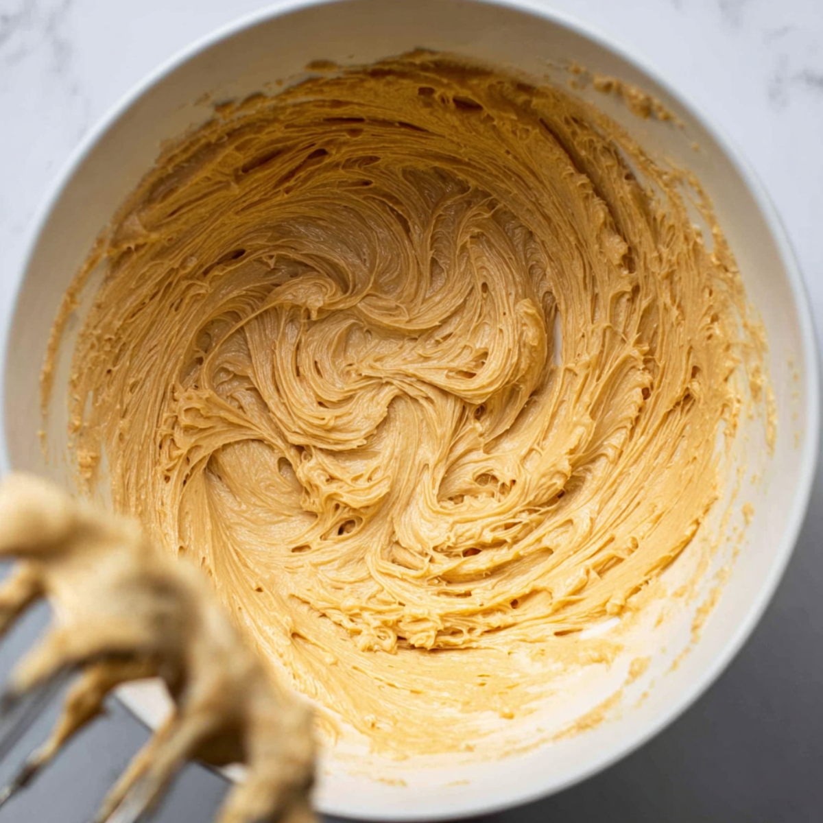 Close up of a mixing bowl with creamed wet ingredients for baking, showing a smooth and creamy texture, perfect for making cookies or other baked goods.
