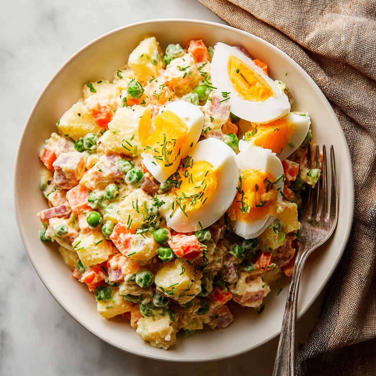 Close up of a bowl of Russian Olivier salad with diced carrots, potatoes, peas, ham, chopped boiled eggs, and green onions, topped with three slices of boiled egg and garnished with chopped chives, served with a fork on a marble countertop, warm natural lighting, high detail, vibrant and appetizing food photography style