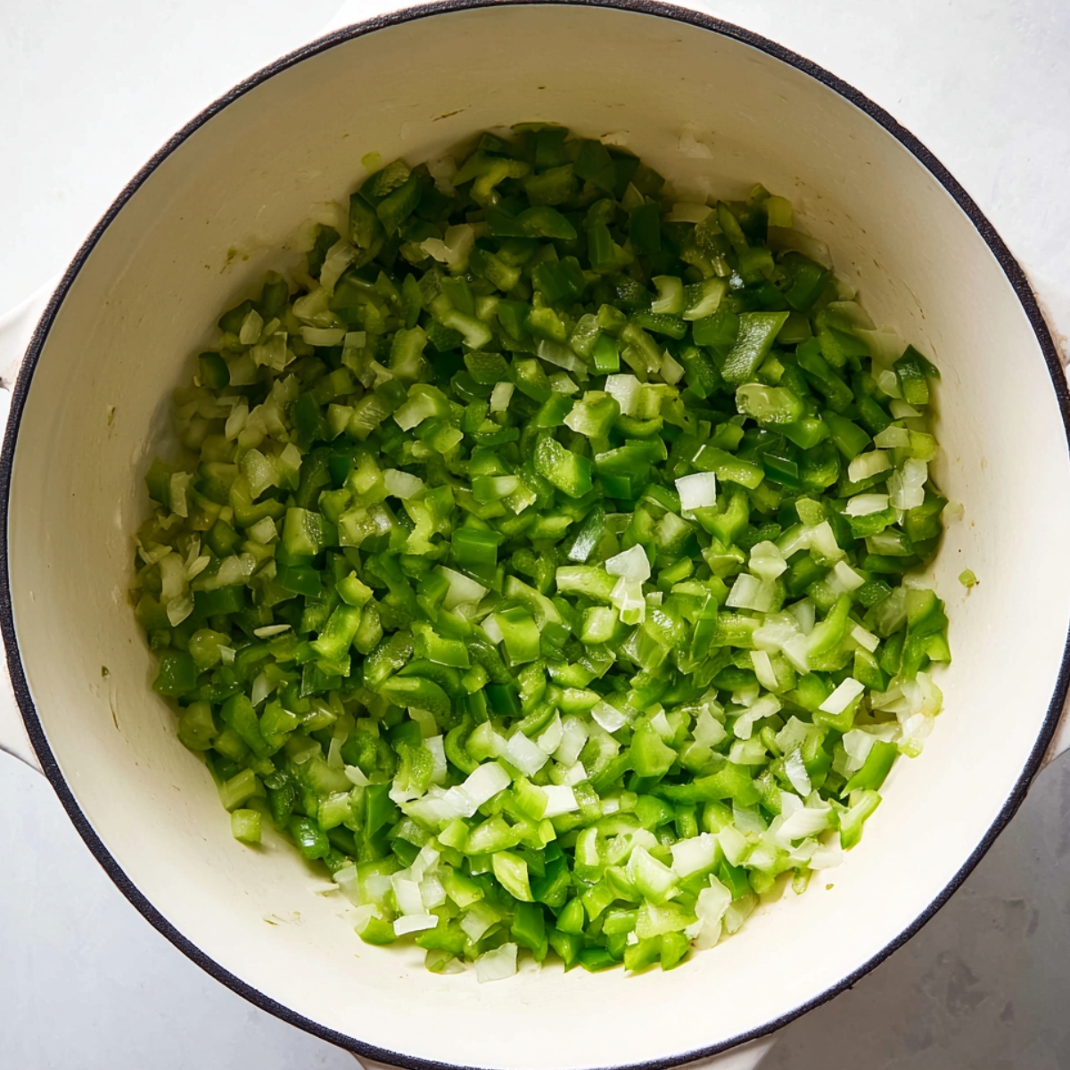 Close up of finely chopped green bell peppers and onions in a white pot, fresh and vibrant, ready for cooking