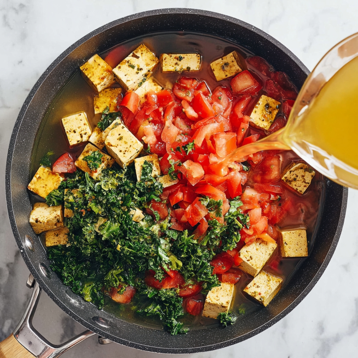 Close up of a skillet with cubed tofu, chopped tomatoes, blended spinach, and herbs being mixed with vegetable broth, vibrant colors, top-down view, bright natural lighting, marble countertop background, high-detail food preparation photography, fresh and healthy ingredients