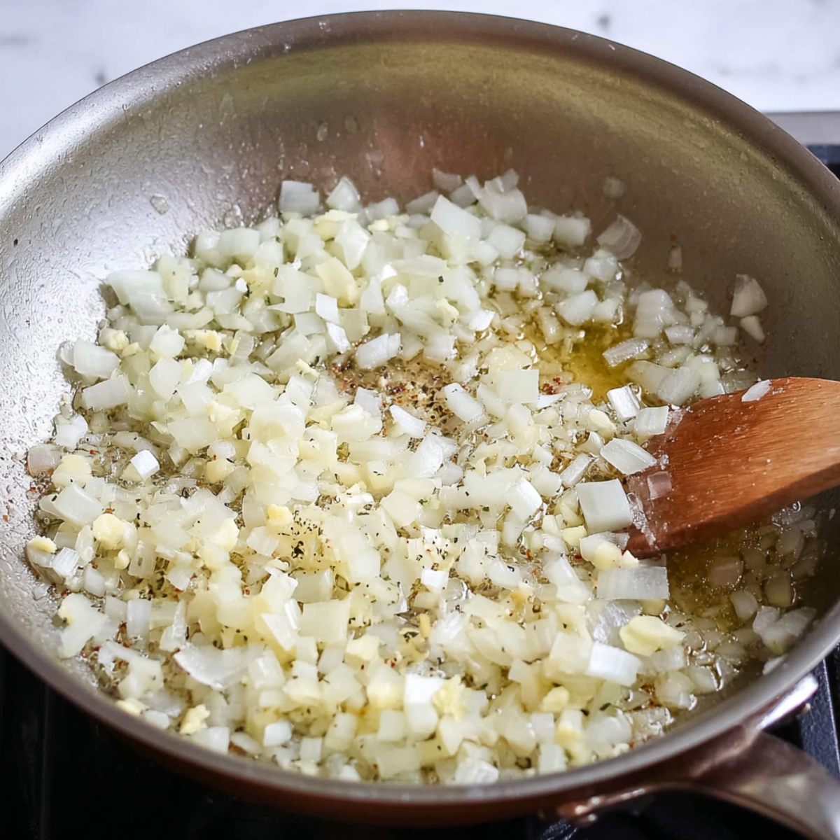 Close up of onions and garlic sizzling in a pan with butter, creating a rich and aromatic base for a savory dish.